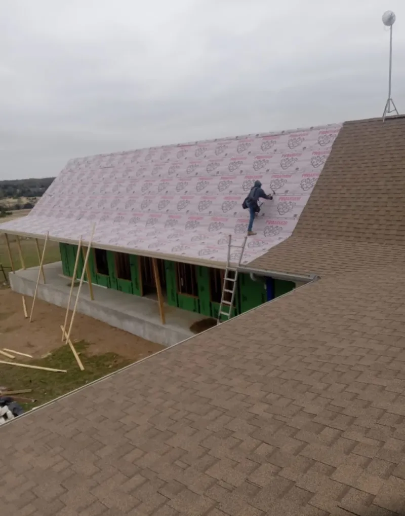 Worker preparing underlayment for a metal roof installation in Broussard